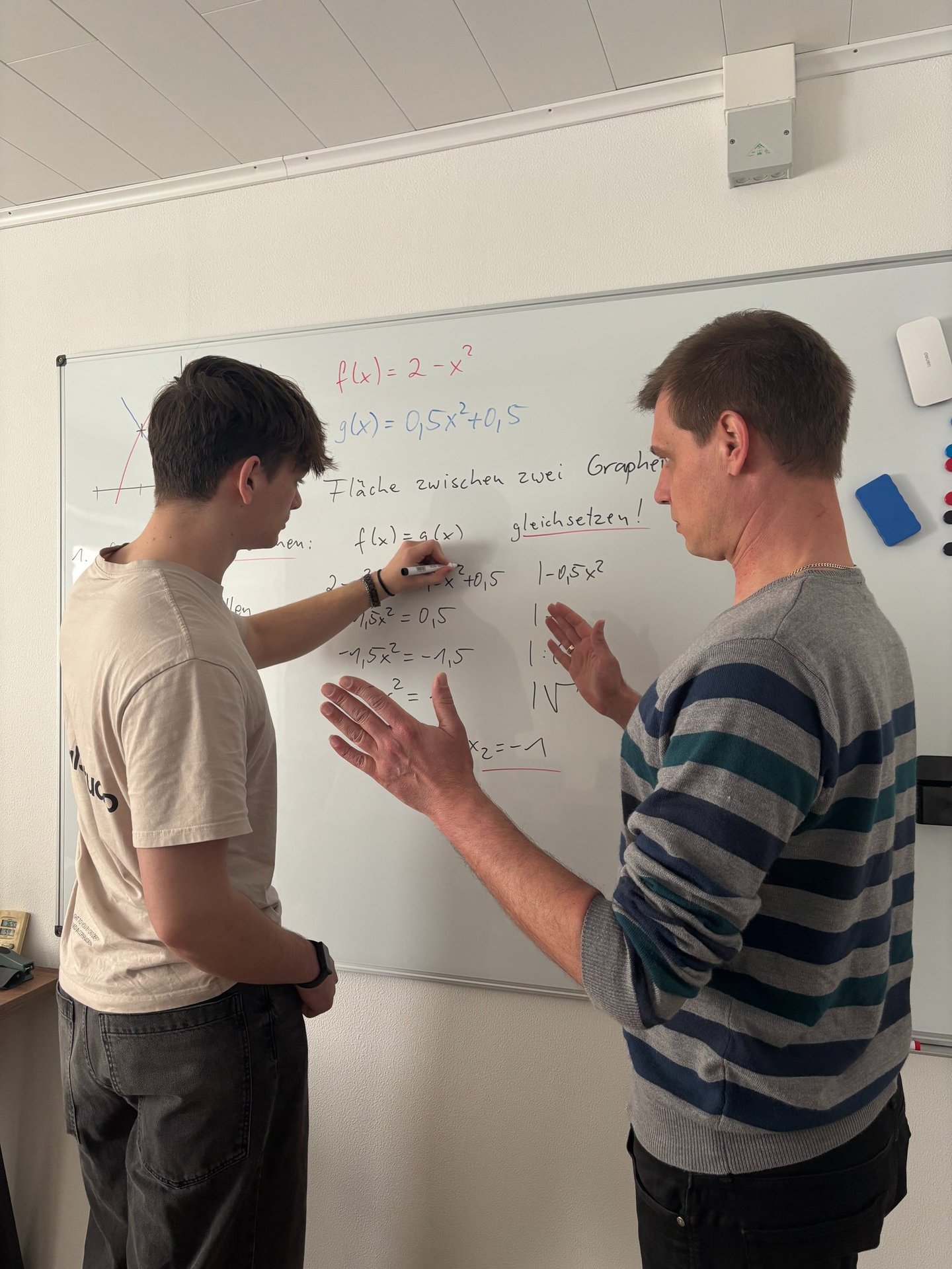 Niclas Klein erklärt einem Schüler am Whiteboard eine Mathematikaufgabe
